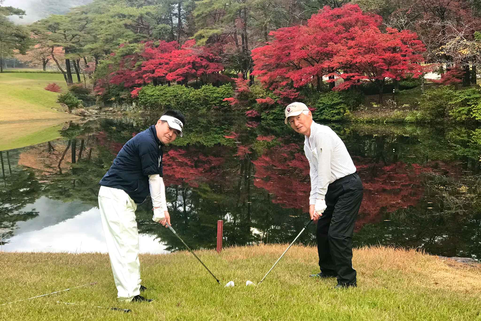 紅葉を背景に、関西ゴルフサークル セブンエイトの辻さん、澤口さん2人の写真
