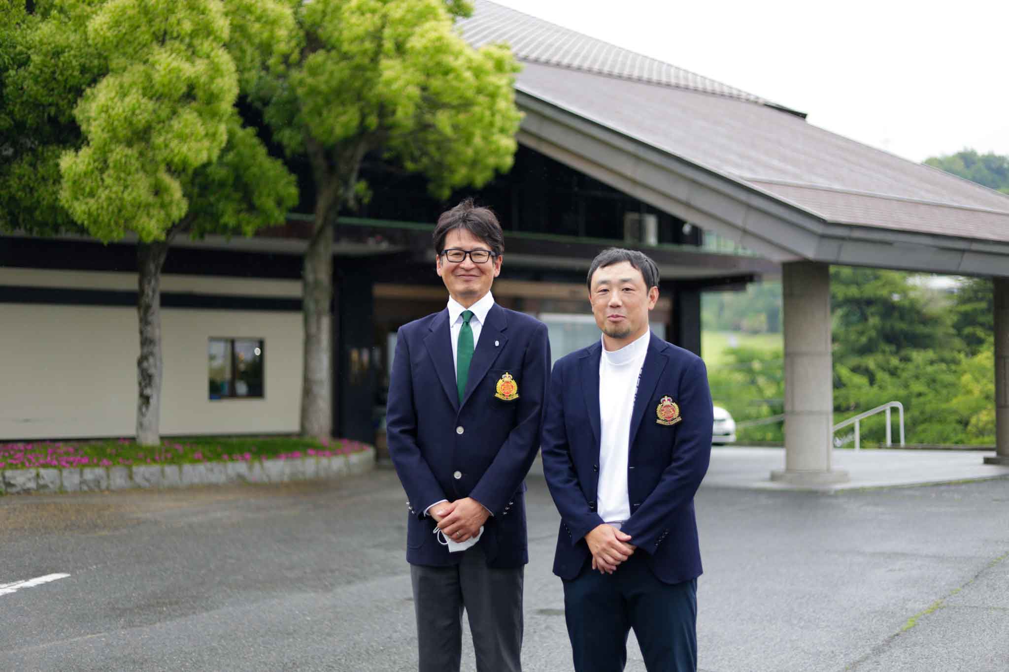 枚方国際ゴルフ倶楽部の玄関前で支配人と記念写真する平田雅也さん